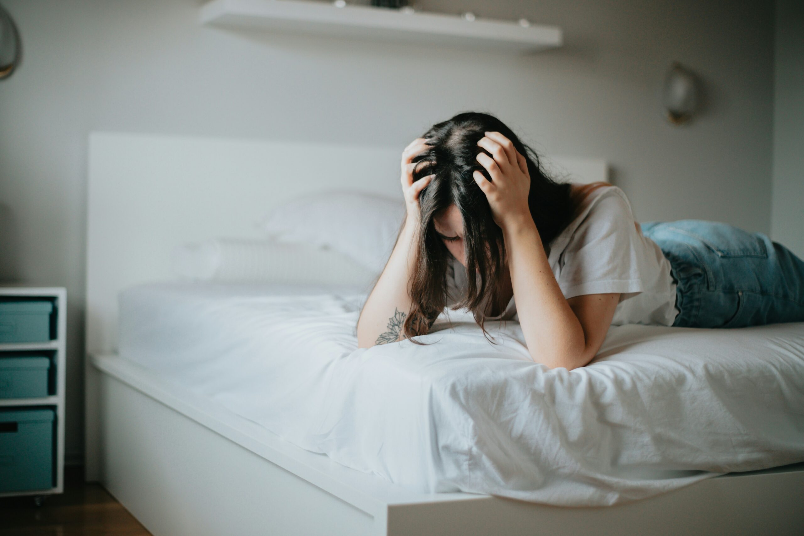 Frau auf Bett, die sich die Haare rauft