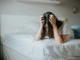 Frau auf Bett, welche sich die Haare rauft