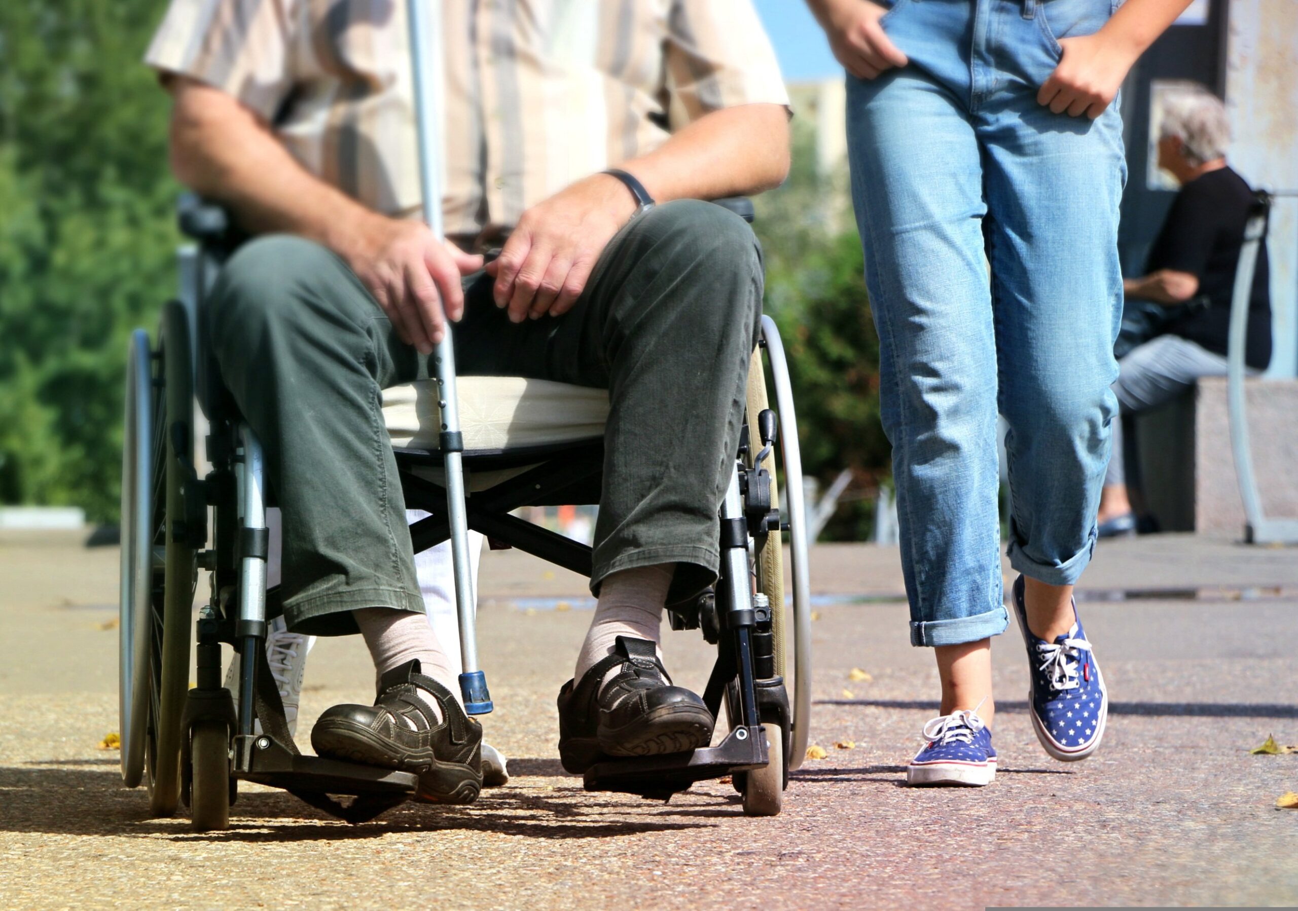 2 people from the waste down. one in a wheel chair, one on foot