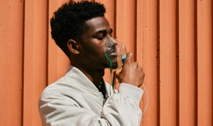 man holding a breathing mask to his face and inhaling deeply.