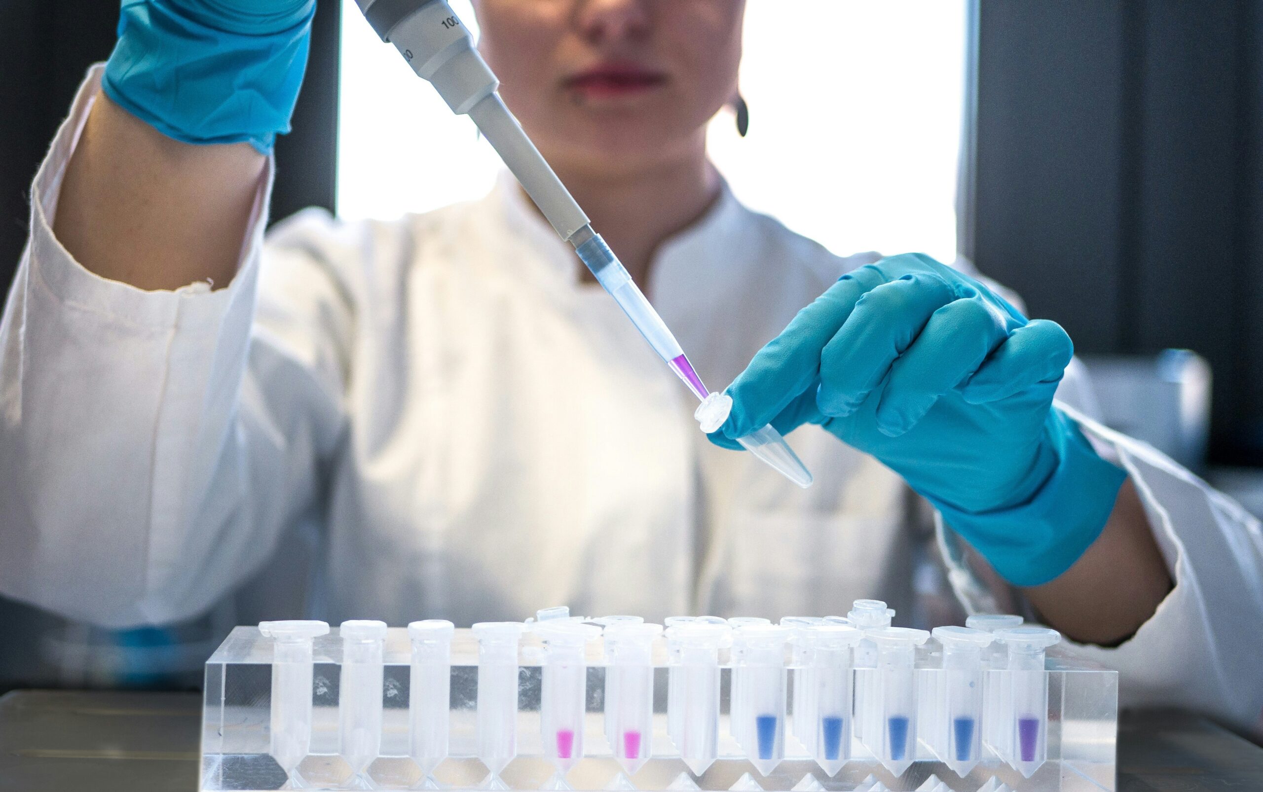 woman in a laboritory setting filling pipettes with a liquide 