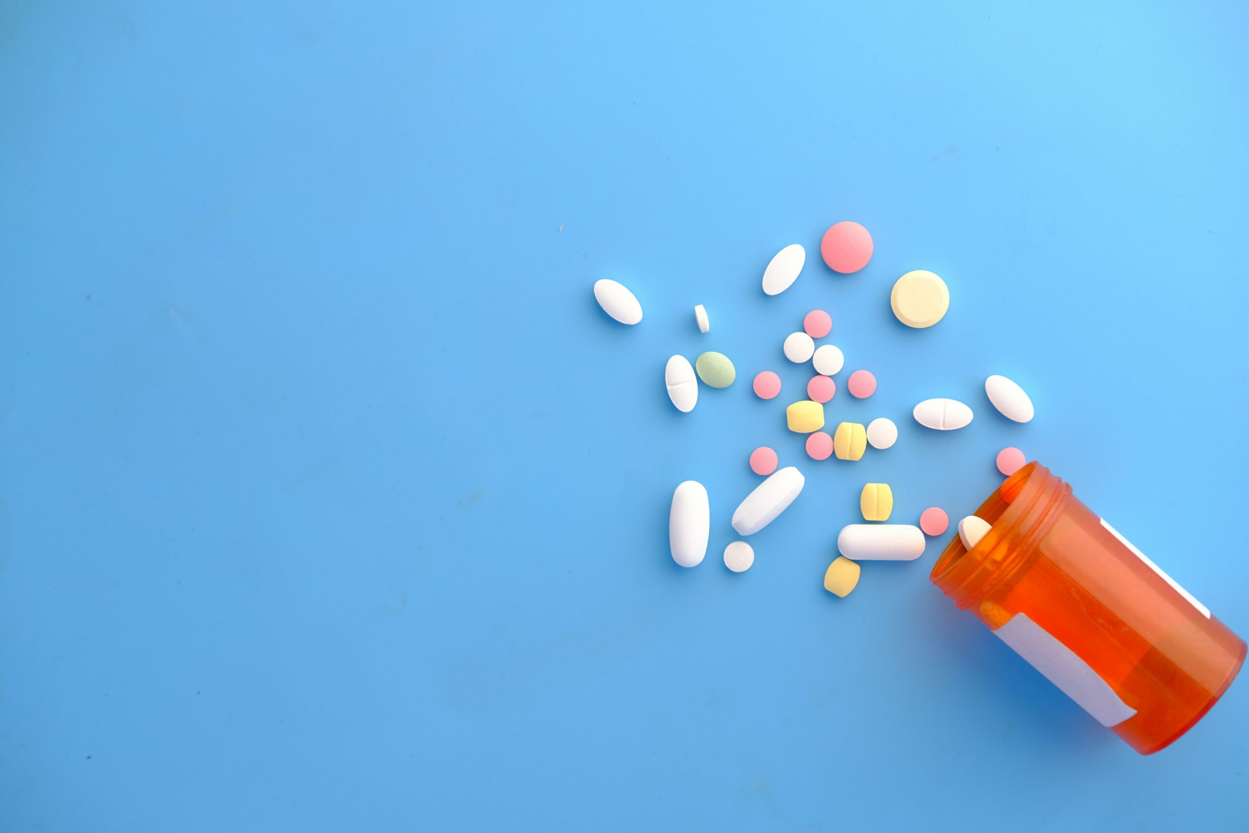 bottle of spilled pills on blue background