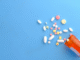 bottle of spilled pills on blue background