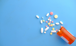 bottle of spilled pills on blue background