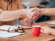 two people shaking hands over a desk