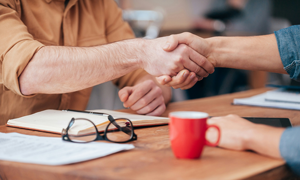 two people shaking hands over a desk